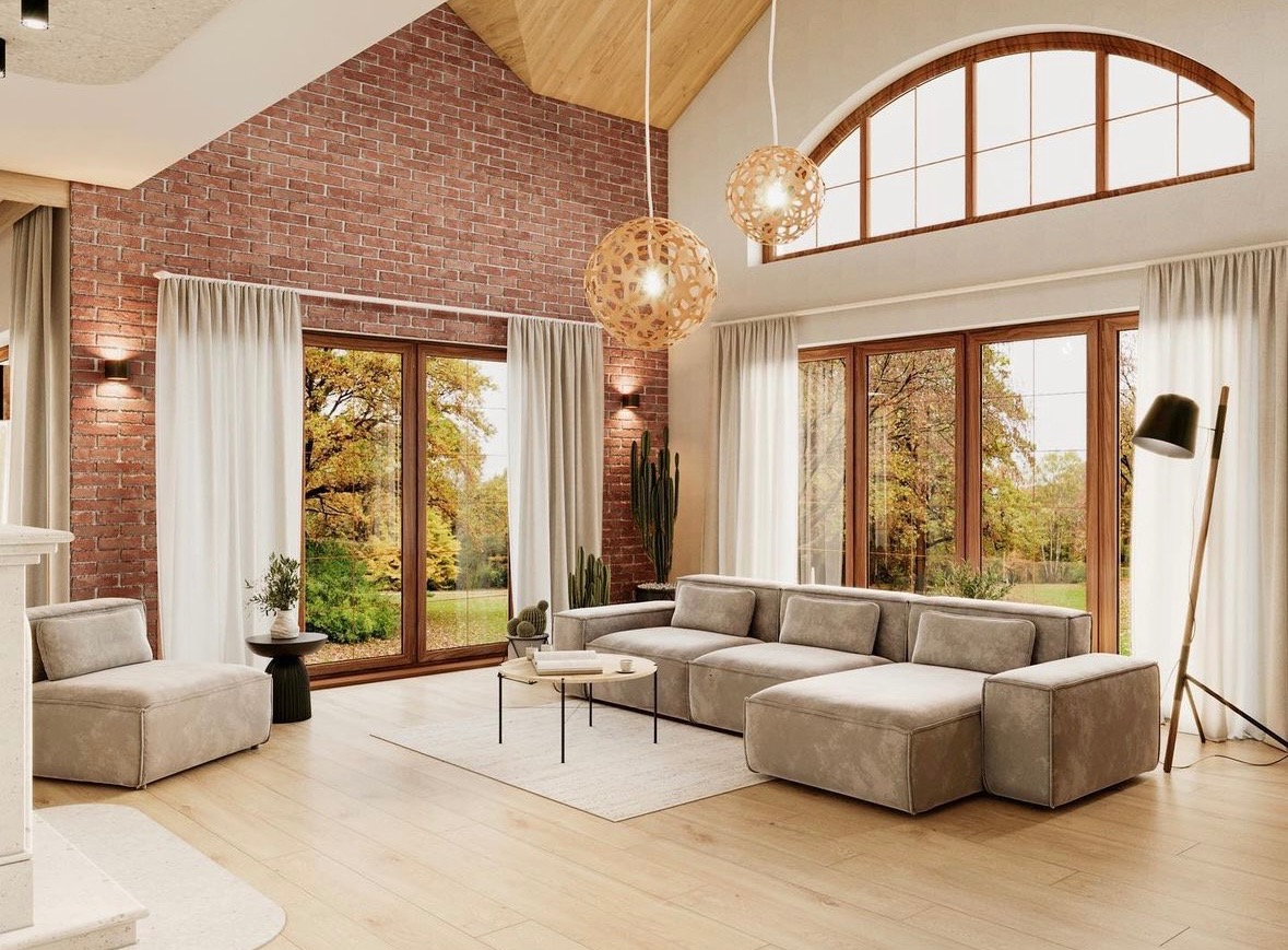 Jasne wnętrze salonu z ceglaną ścianą, dużymi oknami z widokiem na jesienny ogród, beżową sofą modułową, drewnianą podłogą i ażurowymi lampami wiszącymi.