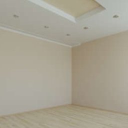 Paweł Mroszczyk - Jasne wnętrze po remoncie: kremowe ściany, drewnopodobne panele, białe drzwi i sufit z oświetleniem punktowym. Minimalistyczny design, gotowe do zamieszkania.