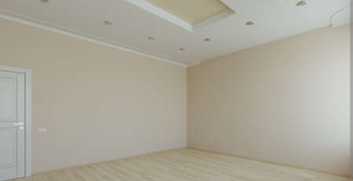 Jasne wnętrze po remoncie: kremowe ściany, drewnopodobne panele, białe drzwi i sufit z oświetleniem punktowym. Minimalistyczny design, gotowe do zamieszkania.