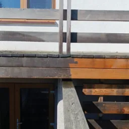 Fragment drewnianego tarasu przed i po czyszczeniu, widoczna różnica w kolorze drewna, z lewej strony powierzchnia nieczyszczona, z prawej odświeżona, jaśniejsza.