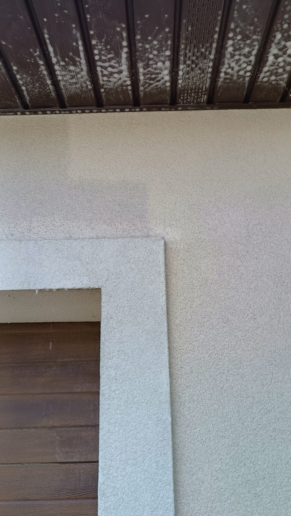 Fragment elewacji po czyszczeniu: widoczna różnica w kolorze i strukturze między czystą a zabrudzoną powierzchnią. Drewniana podbitka z białymi zaciekami.