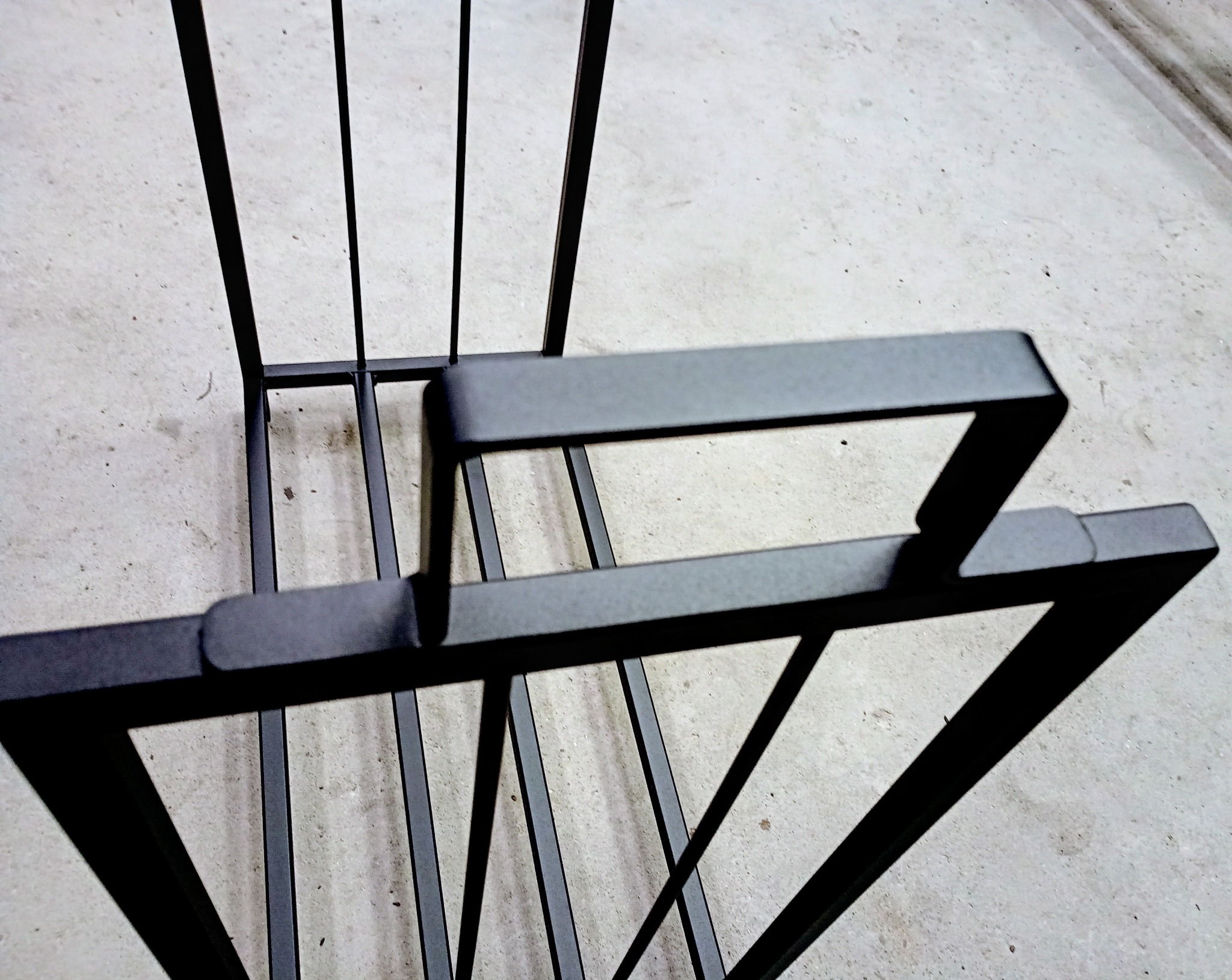 Metalowy stelaż z profili kwadratowych malowanych proszkowo, widok z góry na szarym tle betonowej posadzki.