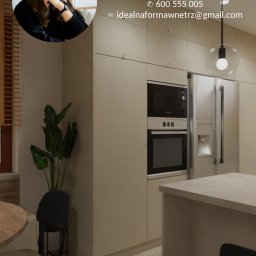 IdealForm Natalia Gosztyła - Wizualizacja kuchni w odcieniach beżu z zabudową meblową, sprzętami AGD i wyspą; w rogu widoczna roślina doniczkowa, nałożone dane kontaktowe i logo firmy.