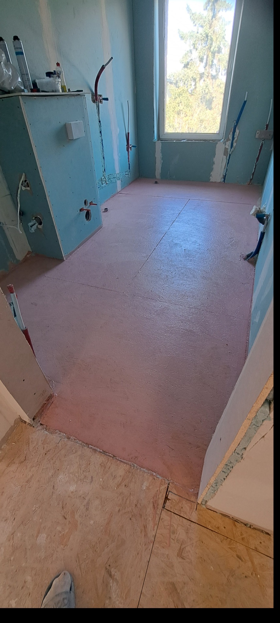 Stan surowy łazienki w Szczecinie przed wykończeniem: płyta OSB na podłodze, ściany z płyt kartonowo-gipsowych, instalacje wodne wyprowadzone.