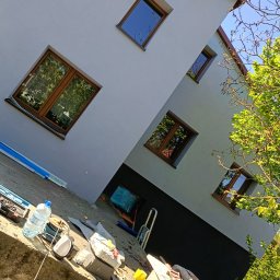 MAR-BUD Mateusz Potyński - Elewacja budynku po remoncie z nowymi oknami, widok z dołu. Na pierwszym planie narzędzia i materiały budowlane. Ujęcie z perspektywy żabiej.