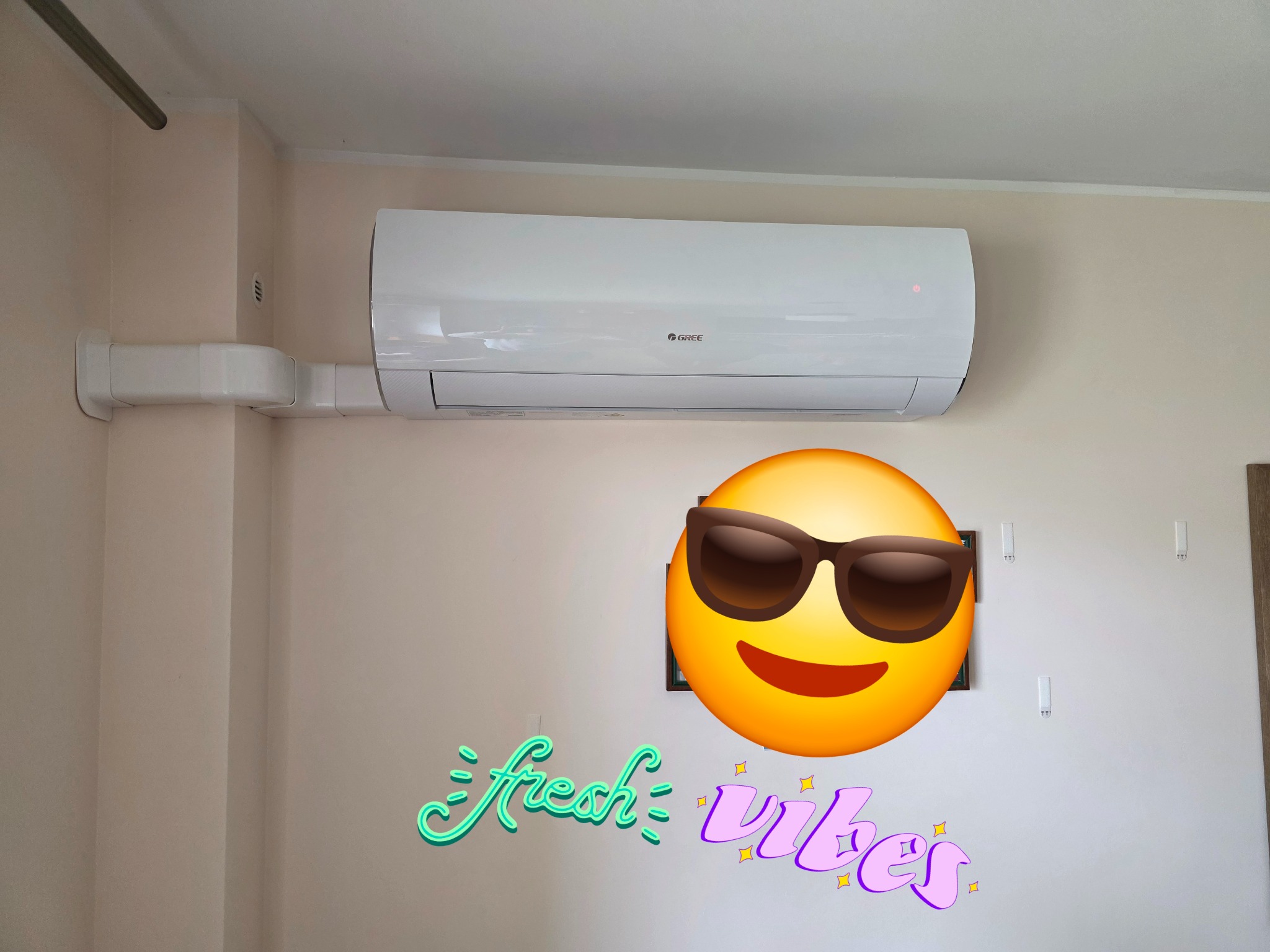 Biała klimatyzacja Gree na ścianie, z widocznymi przewodami. Dodano emoji i napis 'fresh vibes'.