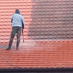 Elewacje-mycie-malowanie. - Czyszczenie dachu z dachówki ceramicznej za pomocą myjki ciśnieniowej. Widoczna różnica w kolorze między czystą a zabrudzoną powierzchnią.