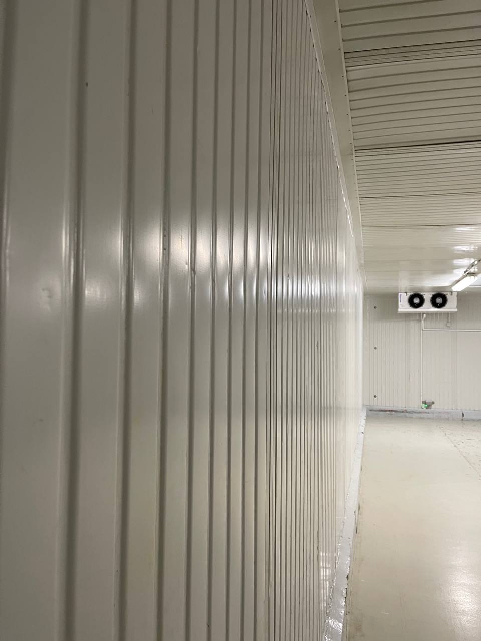 Wnętrze czystego, przemysłowego pomieszczenia z panelowymi ścianami i klimatyzacją, widok z perspektywy podłogi.