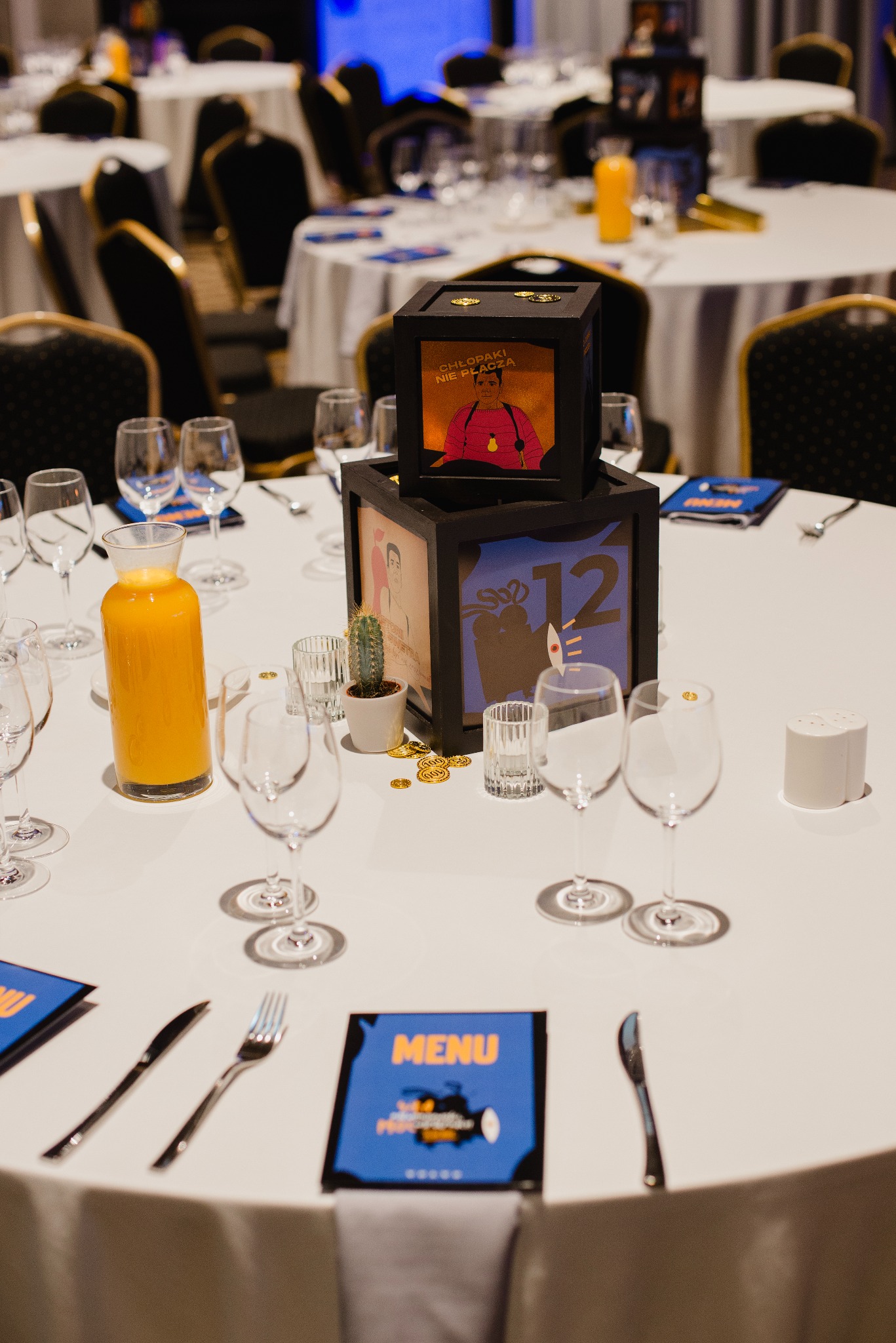 Dekoracja stołu na imprezie firmowej z elementami nawiązującymi do polskiej kinematografii, numeracja stołów w formie czarnych, drewnianych kostek.