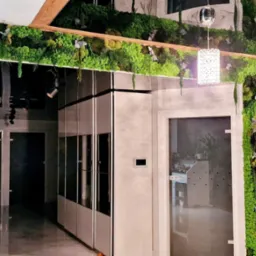Nowoczesne wnętrze z pionowymi panelami z mchu i roślin, drewniana drabina dekoracyjna, szklane drzwi i szafy w tle, oświetlenie punktowe i wisząca lampa.