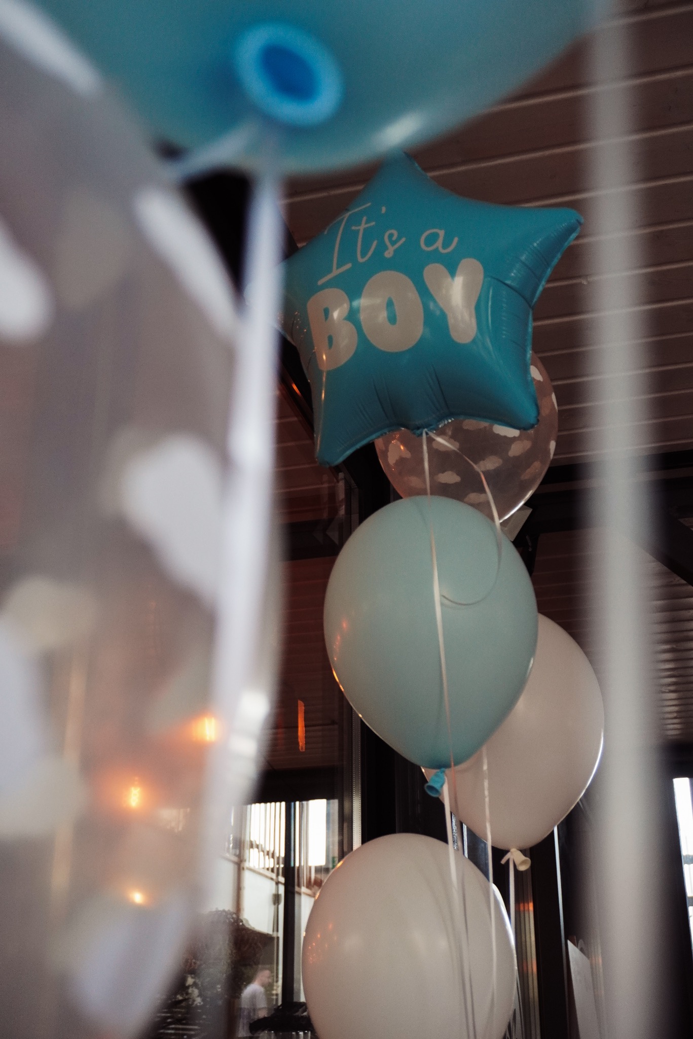 Dekoracja balonowa z niebieskim balonem w kształcie gwiazdy z napisem 'It's a BOY' i białymi balonami, prawdopodobnie na przyjęciu z okazji narodzin dziecka.