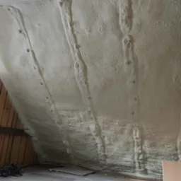 Poddasze w Wołczynie po natrysku pianki poliuretanowej, widoczne drewniane elementy konstrukcyjne i okno.