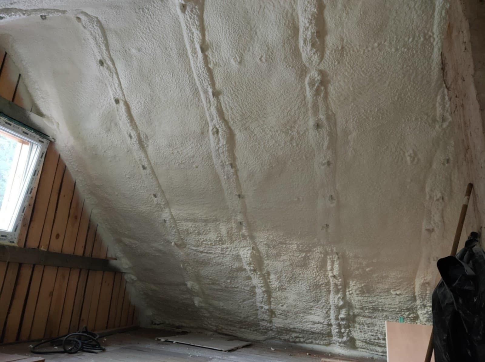 Poddasze w Wołczynie po natrysku pianki poliuretanowej, widoczne drewniane elementy konstrukcyjne i okno.