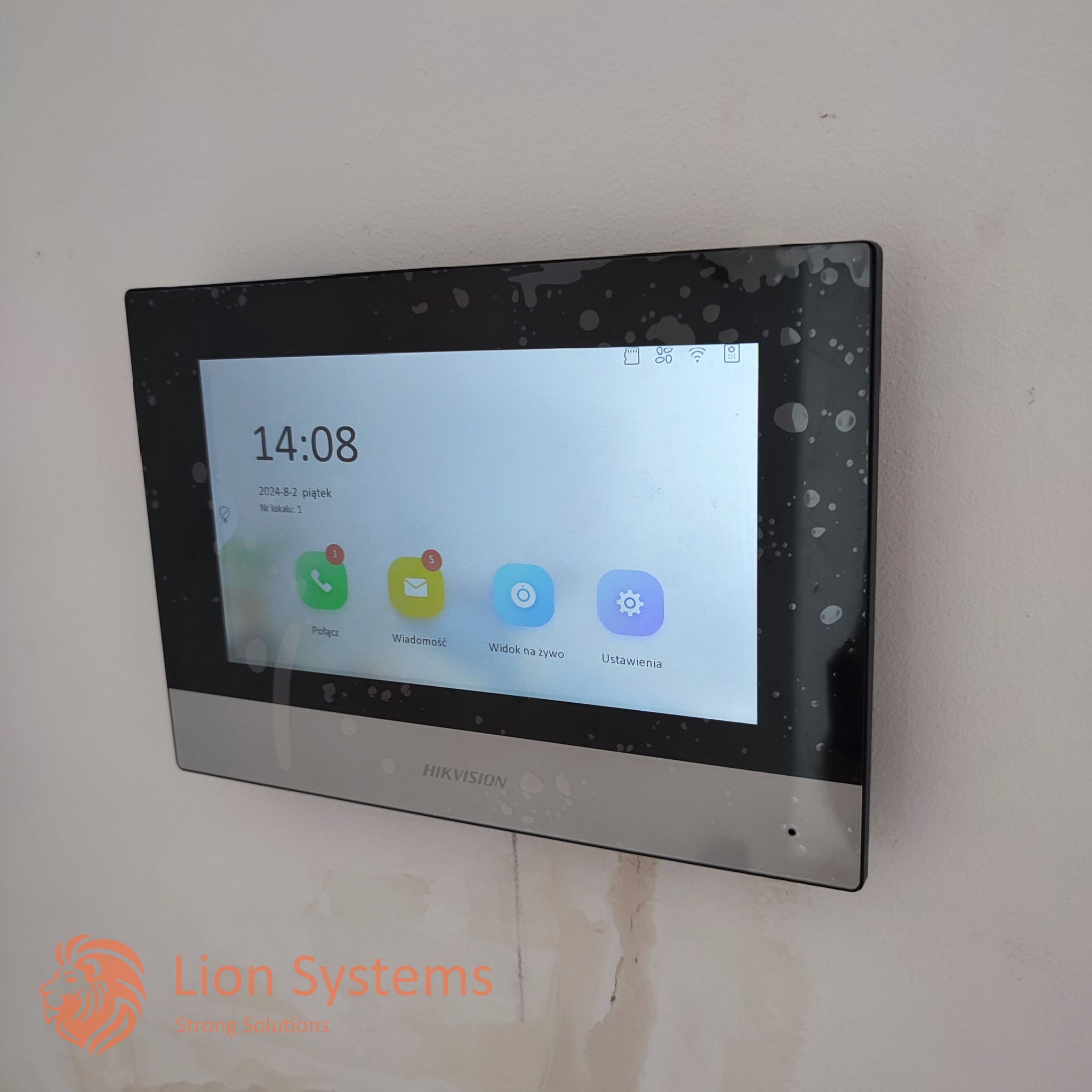 Panel dotykowy wideodomofonu Hikvision zamontowany na ścianie, wyświetlający godzinę 14:08, datę 2 sierpnia 2024, oraz ikony połączeń, wiadomości, podglądu na żywo i ustawień.