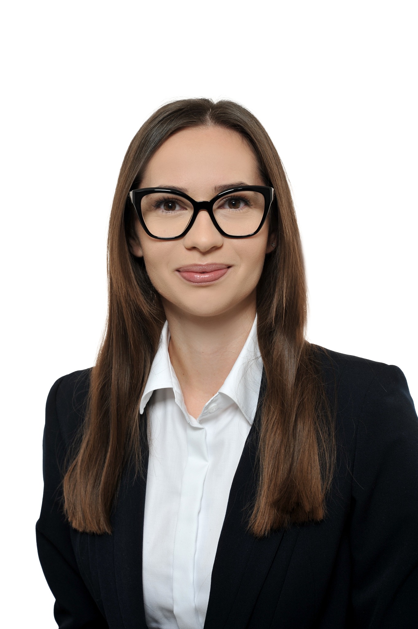 Portret młodej kobiety w okularach i czarnym żakiecie na białym tle, uśmiechająca się.