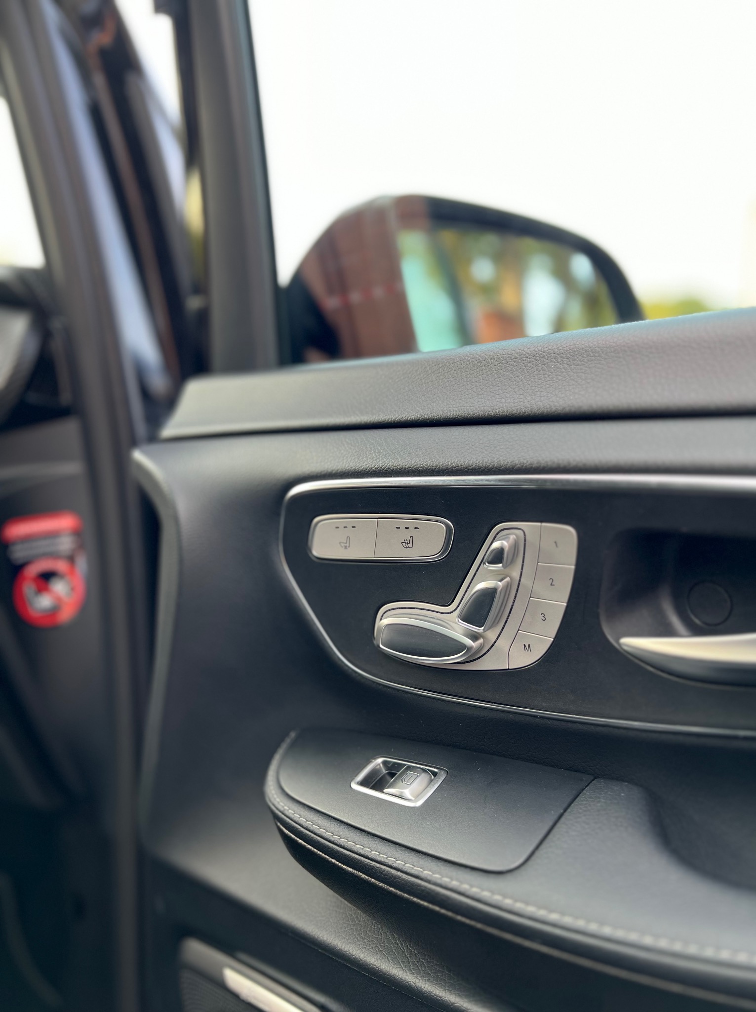 Panel sterowania fotela pasażera z chromowanymi przyciskami regulacji w luksusowym busie w Strudze, widoczne także przyciski pamięci ustawień.