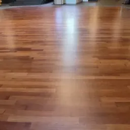 Duża powierzchnia parkietu z ciemnego drewna, po renowacji, widoczne odbicia światła.