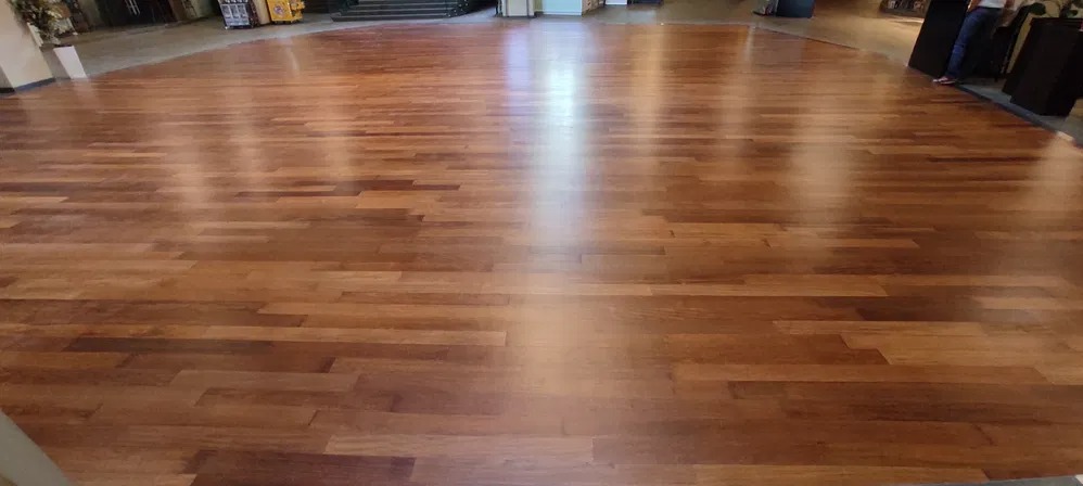 Duża powierzchnia parkietu z ciemnego drewna, po renowacji, widoczne odbicia światła.