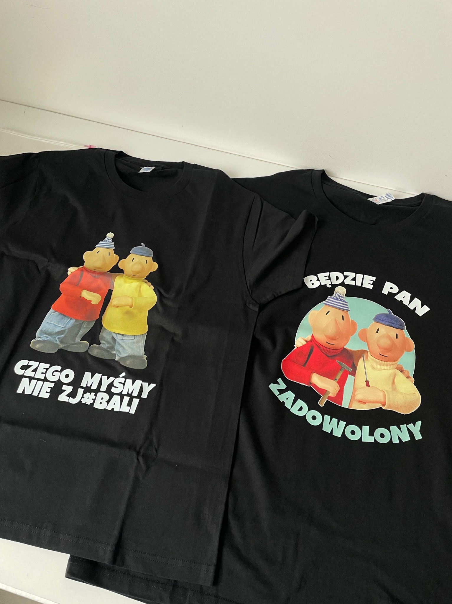 Dwa czarne T-shirty z nadrukami postaci z bajki Pat i Mat oraz napisami 'Czego myśmy nie zj#bali' i 'Będzie Pan zadowolony'