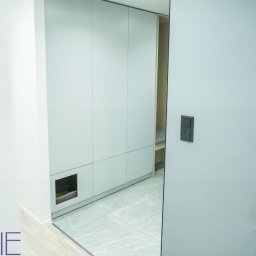 Kuchnie na wymiar Warszawa DMKUCHNIE - Nowoczesna szafa wnękowa z szarymi frontami i małą wnęką dla zwierząt, widoczna z perspektywy wnętrza w mieszkaniu w Warszawie.