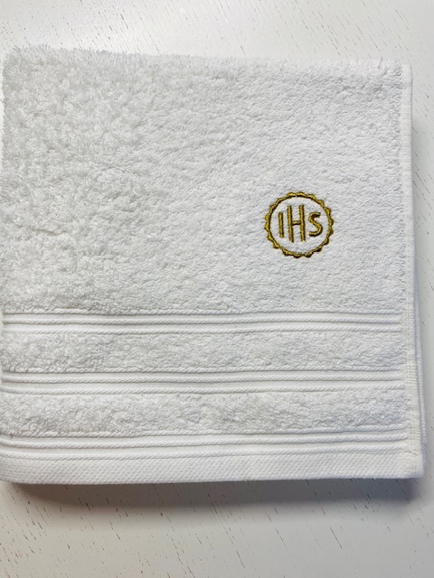 Biały ręcznik frotte z ozdobnym, złotym haftem IHS, wykonany w Łukowie. Elegancki detal i wysoka jakość wykonania.
