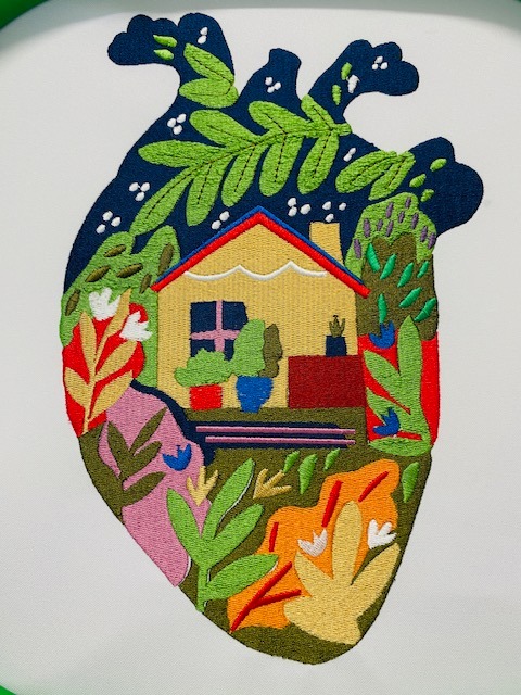 Haftowane serce z motywem domu i roślin, kolorowe detale, unikalny wzór na białym tle, precyzyjne wykonanie, widoczne ściegi.