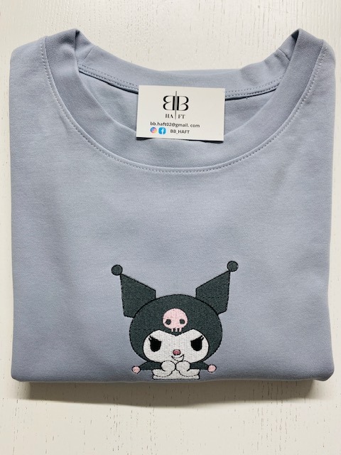 Jasnoszara bluza z haftowaną postacią Kuromi i wizytówką BB HAFT, leżąca na jasnym tle. Precyzyjne detale haftu i neutralne tło podkreślają jakość wykonania.