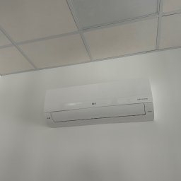 MR INSTAL - Biała klimatyzacja LG Dual Inverter zamontowana na białej ścianie w pomieszczeniu z kasetonowym sufitem. Widoczny nawiewnik sufitowy.