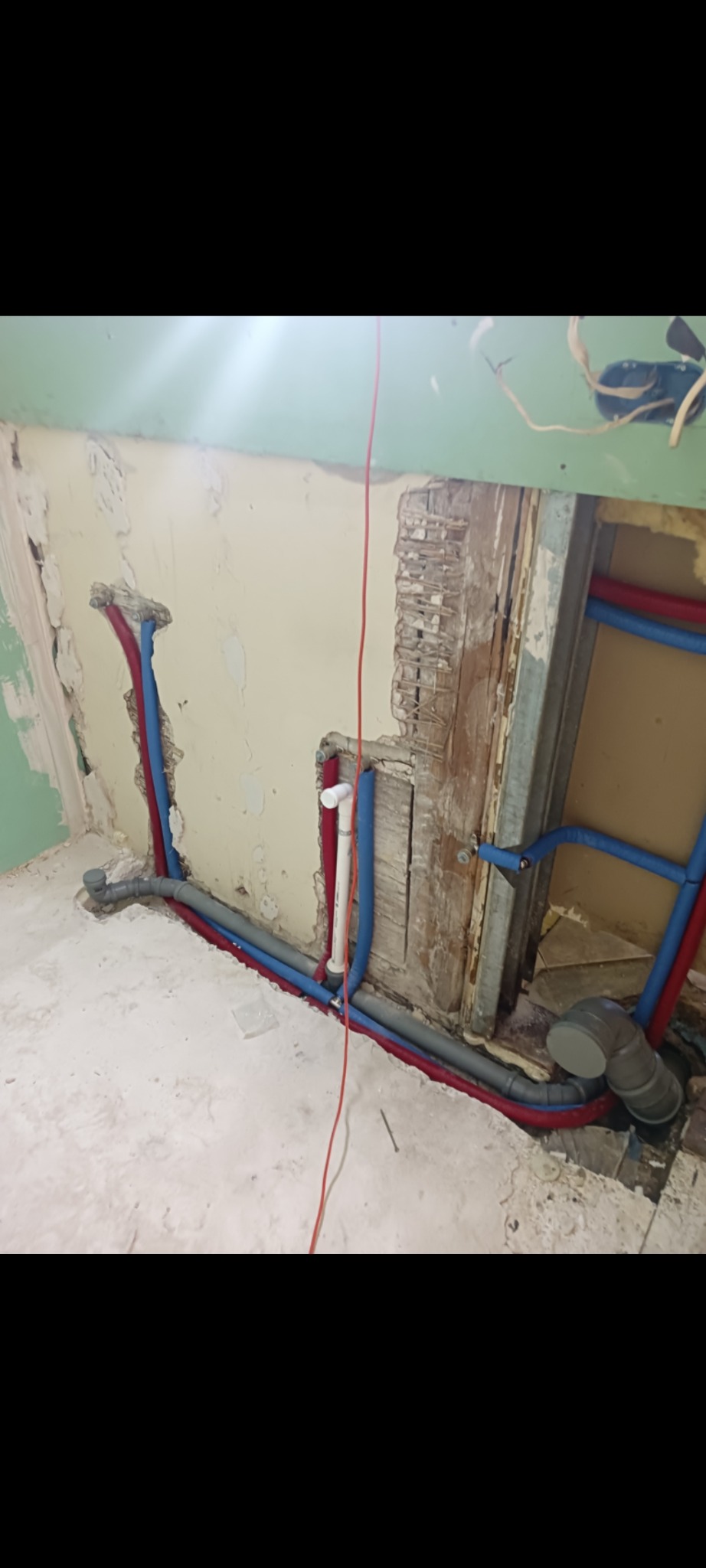 Instalacja wodno-kanalizacyjna w trakcie remontu łazienki: rury w izolacji, surowe ściany, widoczne elementy starej konstrukcji. Etap prac przed wykończeniem.