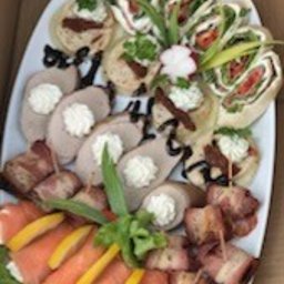 Sala Bankietowa Batory - Elegancka kompozycja przekąsek na białym talerzu: roladki z tortilli, kanapeczki, wędlina z kremem, łosoś z cytryną i bekon. Idealne na firmowe przyjęcie.