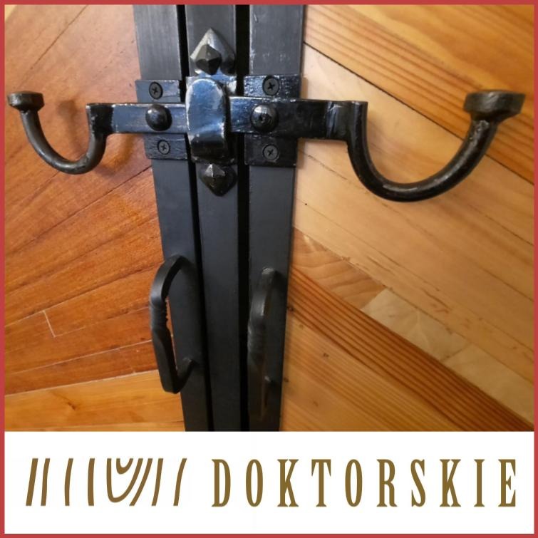 Metalowe okucia w stylu retro na drewnianych drzwiach z desek ułożonych w jodełkę.