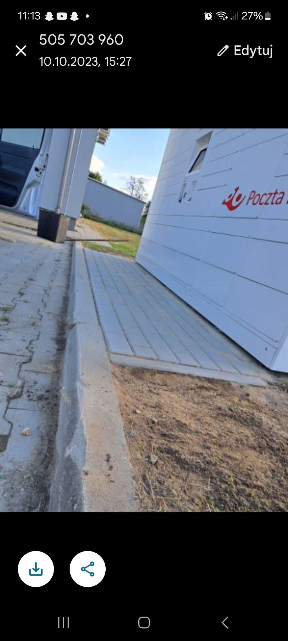 Ułożona kostka brukowa przed budynkiem Poczty Polskiej, widoczny krawężnik i fragment zaparkowanego samochodu dostawczego.