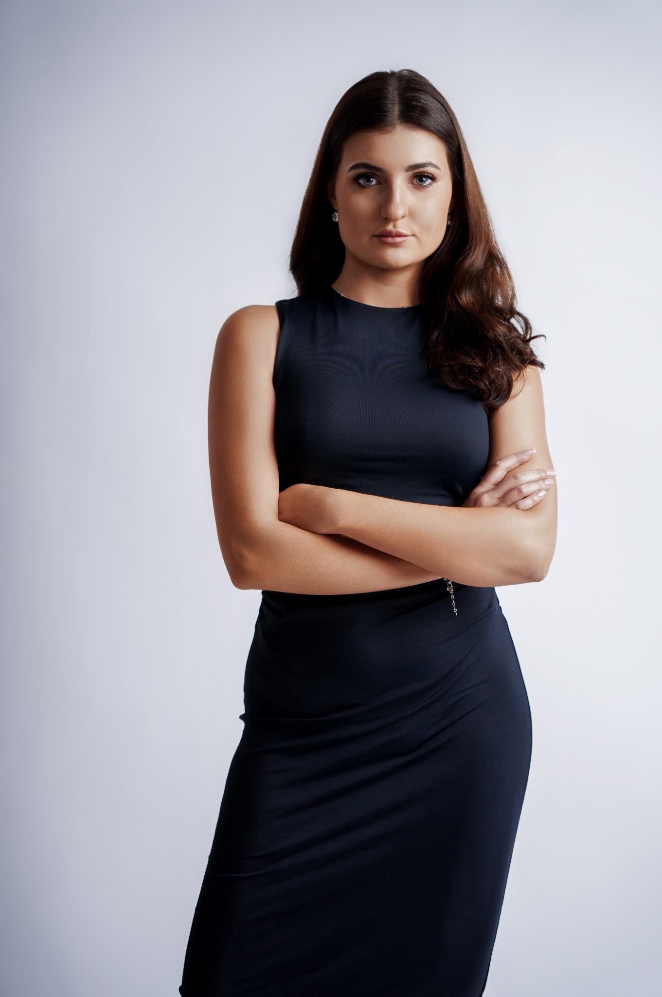 Portret kobiety w granatowej sukience na jasnym tle, ręce skrzyżowane, profesjonalny wygląd, Mikołów.