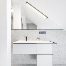 PIK ARCHITEKTURA MARIUSZ ZAŃKO - Nowoczesna łazienka w odcieniach szarości i bieli: wisząca szafka z umywalką, czarna bateria, podświetlane lustro na skośnej ścianie poddasza.