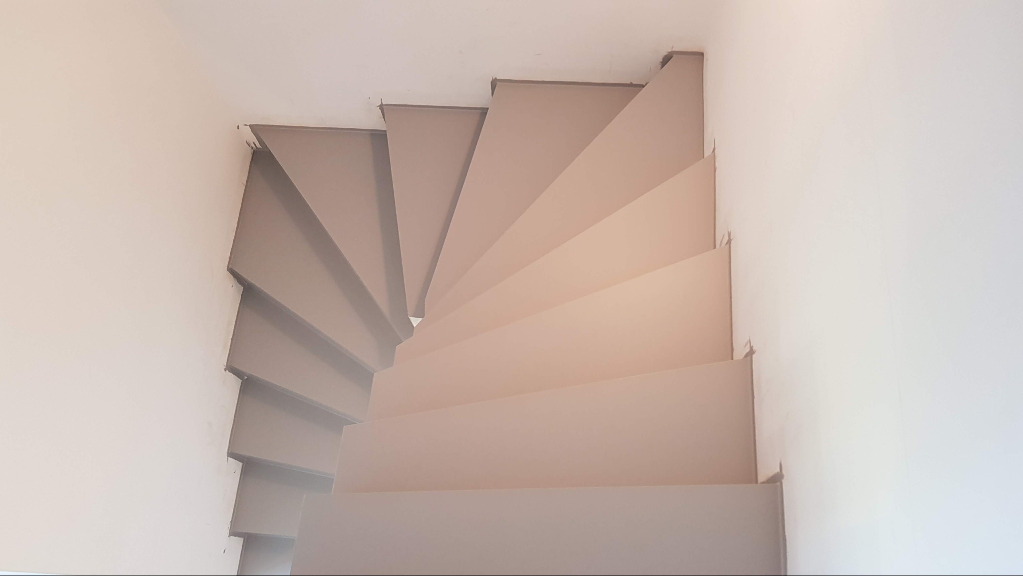 Spiralne schody w Cieszynie, widok z góry, wykończone w jasnych, neutralnych odcieniach, z delikatnym oświetleniem podkreślającym geometrię stopni.