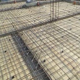 MiAA Budownictwo Mariusz Abramek - Zbrojenie stropu budynku w trakcie budowy, widoczne siatki z prętów stalowych i elementy dystansowe. Przygotowanie do wylewania betonu.