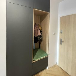 Krzysztof Pęczek, F.H.U. AGMA - Nowoczesna szafa wnękowa z siedziskiem i wieszakami, w odcieniach szarości i drewna, w przedpokoju z parkietem w jodełkę. Minimalistyczny design.