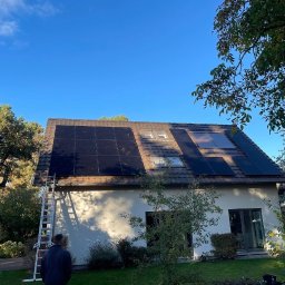 SolarPro Davyd Lytvynets - Dom jednorodzinny z panelami słonecznymi na dachu, drabina oparta o ścianę, widok z dołu, błękitne niebo, drzewa w tle.