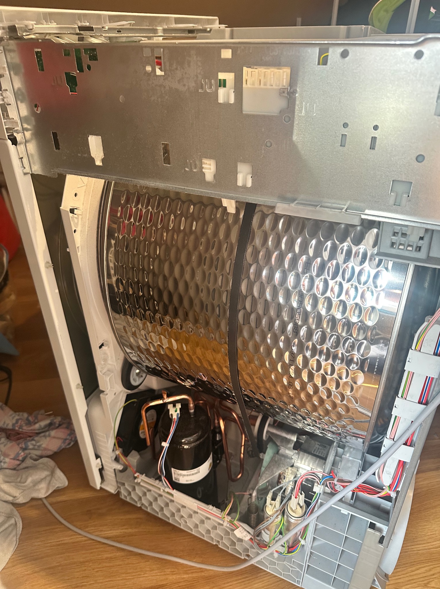 Wnętrze pralki z widocznym bębnem, silnikiem i okablowaniem. Detaliczne ujęcie na podzespoły podczas naprawy lub serwisu urządzenia.