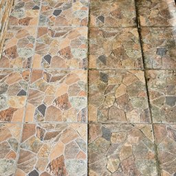 JEST ELEGANCKO MYCIE CIŚNIENIOWE KAROL GOLUBEK - Płytki podłogowe z kamiennym wzorem, część wyczyszczona, część pokryta brudem i mchem. Efekt czyszczenia widoczny na połowie powierzchni.