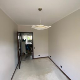 ANDRIY ANDRIISHYN - Jasne, świeżo pomalowane wnętrze z otwartymi drzwiami, przez które widać fragment pokoju. W centralnej części wisi nowoczesna, biała lampa.