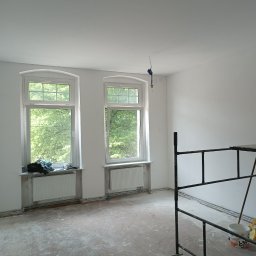 Ivan Husiev - Pokój w Gorzowie Wielkopolskim w trakcie prac przygotowawczych do malowania: widoczne dwa okna z zielenią za szybą, ślady po szpachlowaniu na podłodze i ścianach, oraz fragment rusztowania.