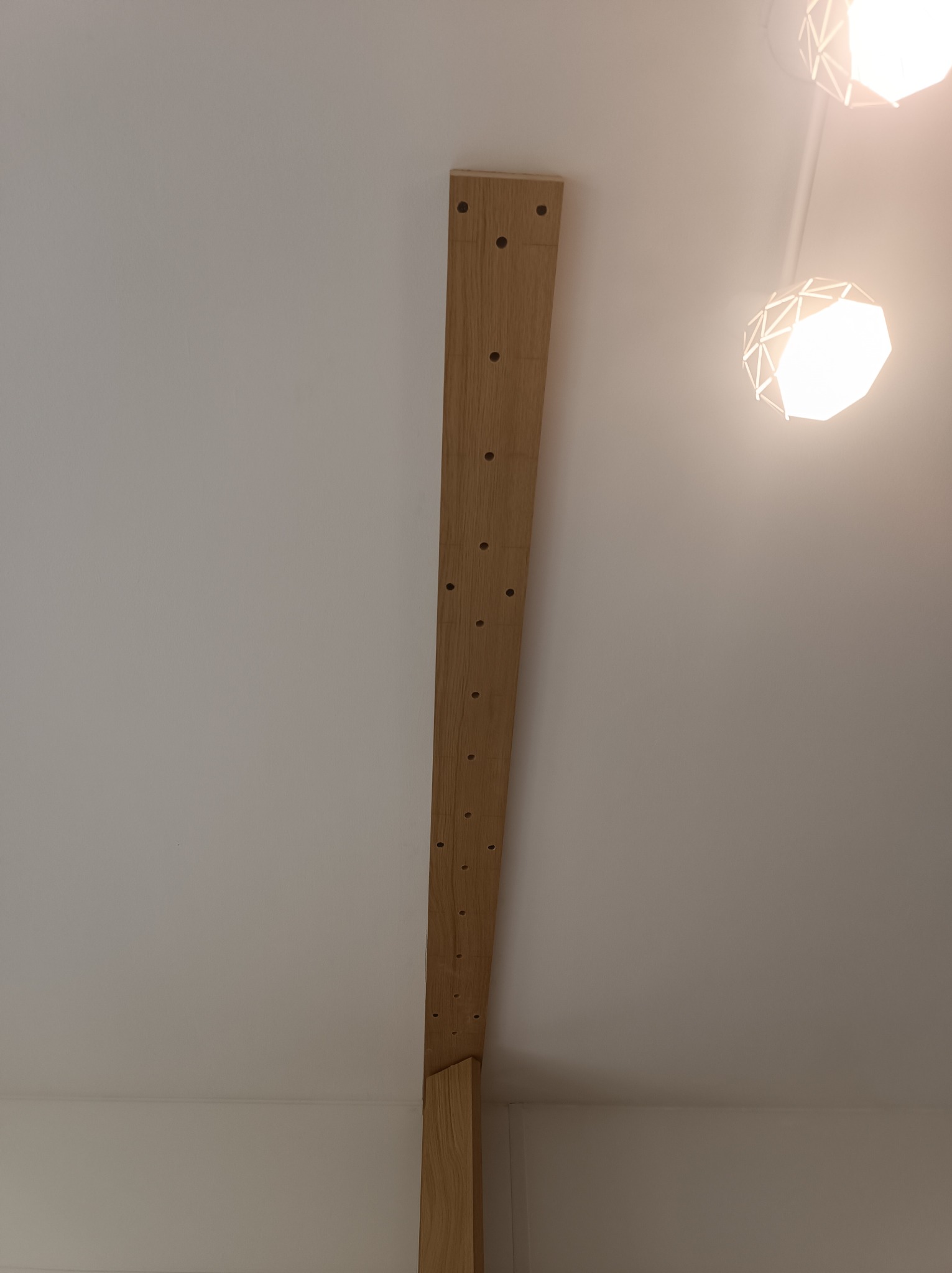 Przygotowanie do montażu płyty karton gips na suficie: widoczny drewniany stelaż z nawierconymi otworami, zamocowany do sufitu w nowym budownictwie, nowoczesna lampa w tle.