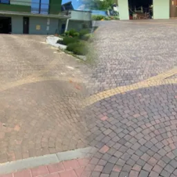 Kostka brukowa przed i po czyszczeniu, widoczna różnica w kolorze i usunięte zabrudzenia. Część posesji z budynkiem w tle. Układana w łuki z obrzeżem z jasnej kostki.