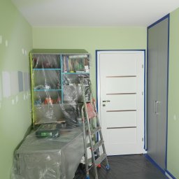 SinggaDruk Filip Sinulingga - Sztuka na każdej ścianie - Pokój w trakcie malowania: zabezpieczone meble folią, drabina oparta o ścianę, testowe kolory na ścianie, taśma malarska przy drzwiach i szafie.