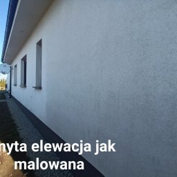 Dariusz Lewandowski - Jasnoszara, umyta elewacja budynku jednorodzinnego z widoczną anteną satelitarną i kamienną opaską przy gruncie.