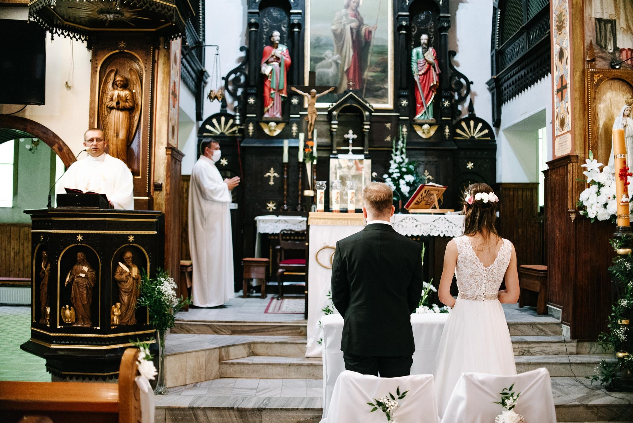 Para młoda podczas ceremonii ślubnej w kościele, ksiądz w maseczce, bogato zdobione wnętrze.