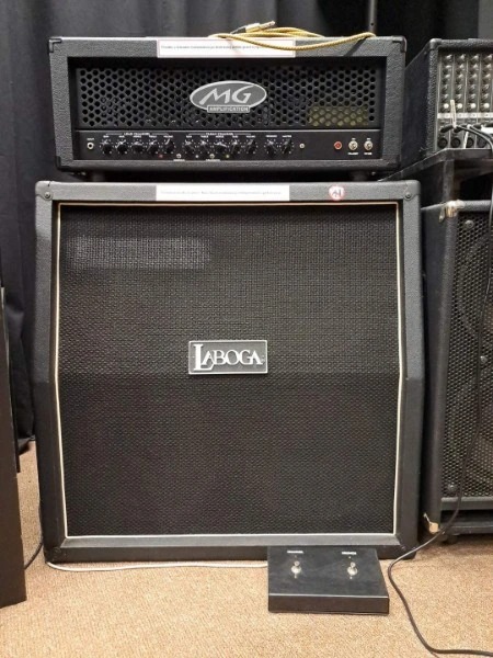 Zestaw wzmacniaczy gitarowych: górny z logo MG Amplification i dolny z logo Laboga, ustawione na podłodze z przełącznikiem nożnym.