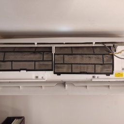 Tworzymy Instalacje Klimatyzacja Warszawa - Wnętrze klimatyzatora ściennego z widocznymi, mocno zabrudzonymi filtrami powietrza, ukazujące potrzebę serwisu i czyszczenia urządzenia.
