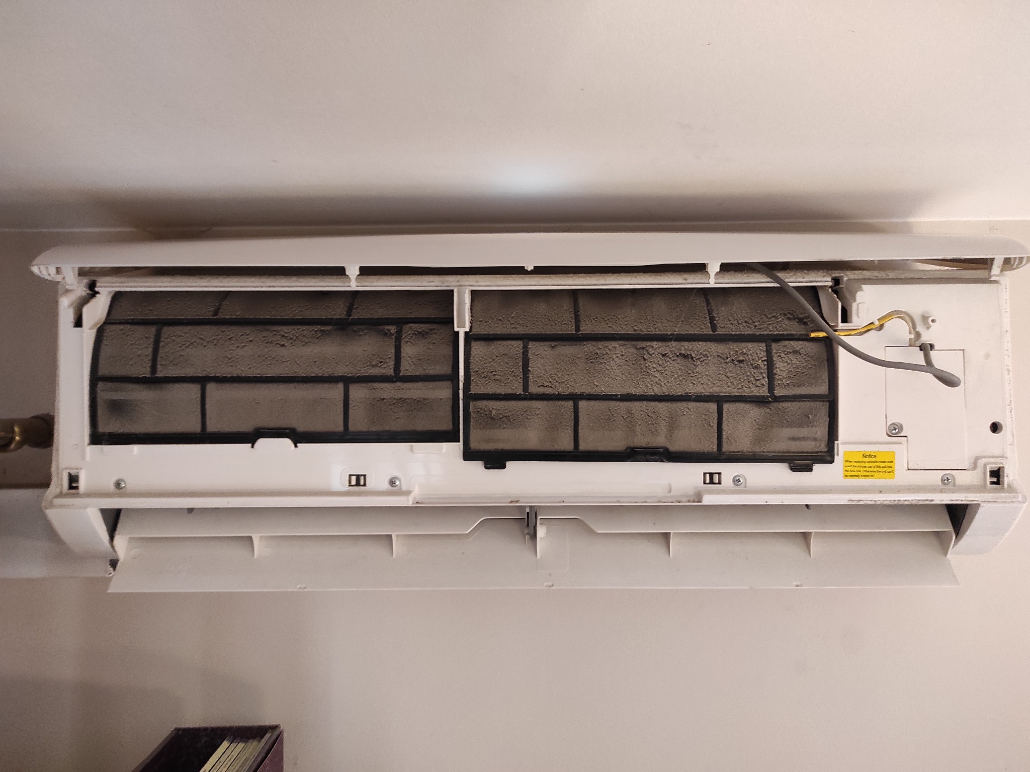 Wnętrze klimatyzatora ściennego z widocznymi, mocno zabrudzonymi filtrami powietrza, ukazujące potrzebę serwisu i czyszczenia urządzenia.